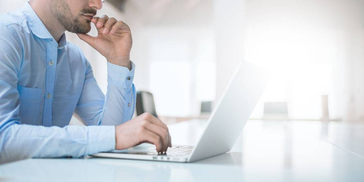 Male in blue shirt looking at laptop.