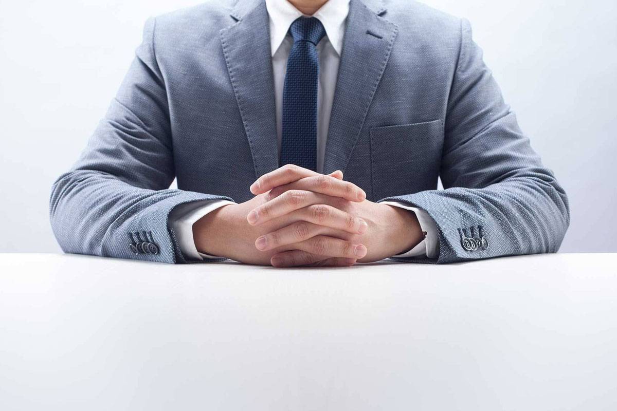 Man wearing grey suite with hands clasped