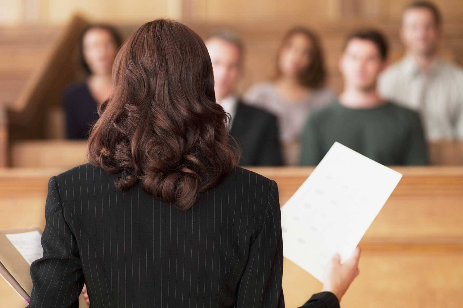 women attorney with dark brown hair standing in front of room holding papers