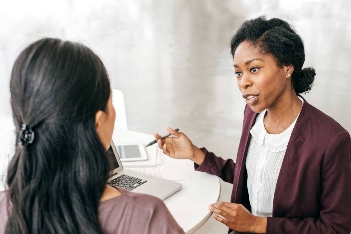 female consultant wearing purple sitting at a desk with another women