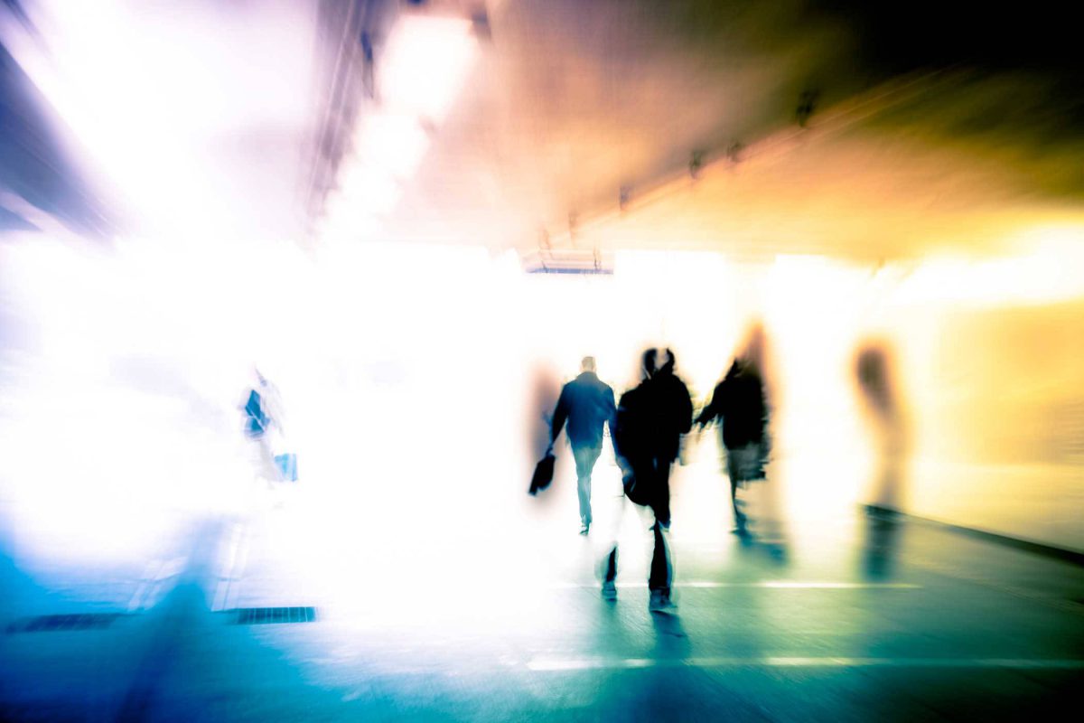 blurred image with people walking and bright light radiating through