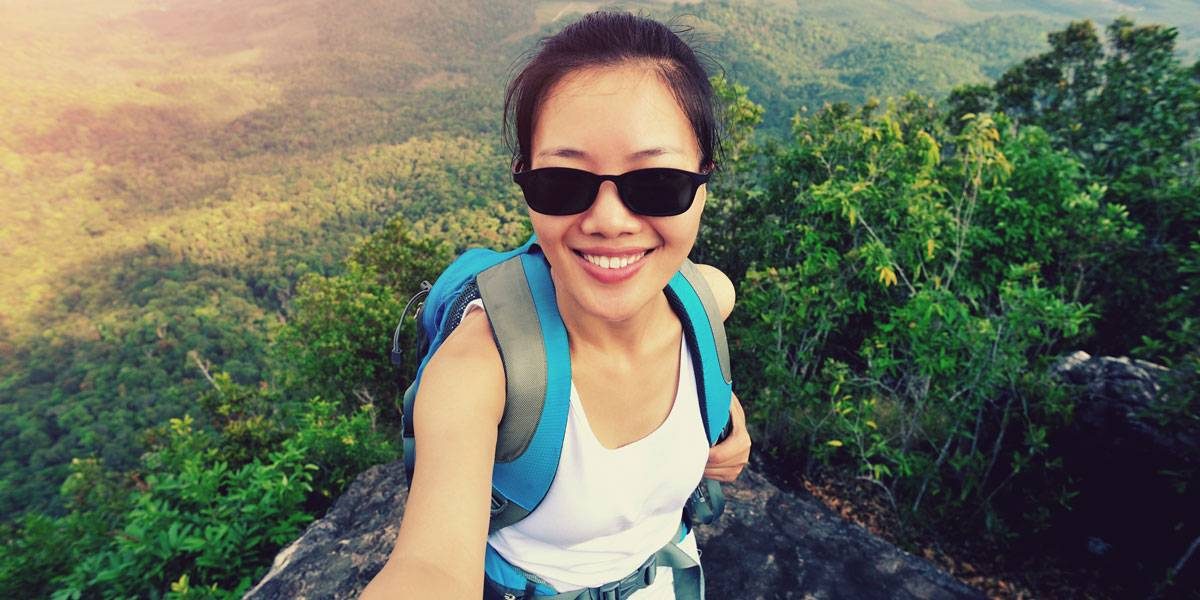 Women standing on edge of cliff taking a selfie